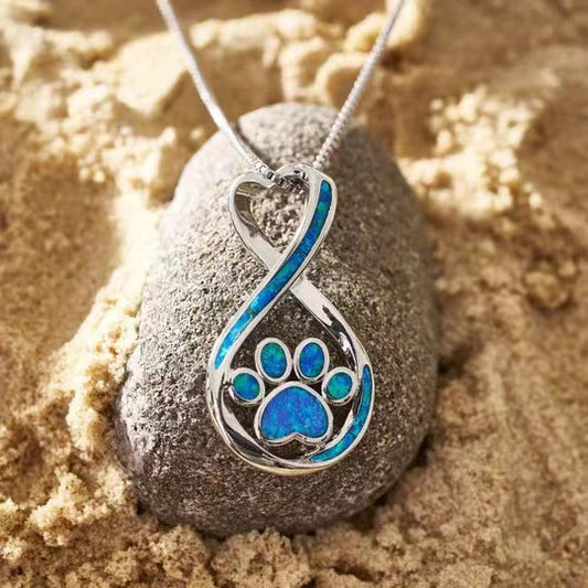 Love paw necklace on sand and stone - atmospheric lifestyle shot